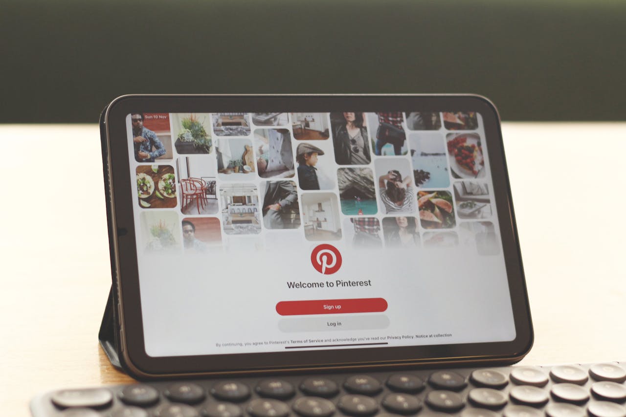 Tablet showing Pinterest homepage on a modern desk setup with a keyboard.